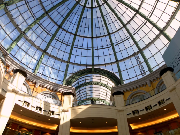 Low-angle view of the iconic glass dome skylight and curved ceiling architecture inside Mall of the Emirates, KhaleejFusion
