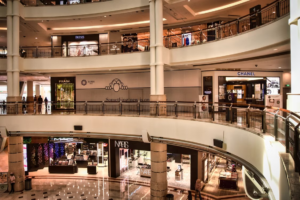 Multi-tier shopping concourse inside Suria KLCC featuring luxury boutiques including Chanel, Prada, and NARS, khaleejFusion