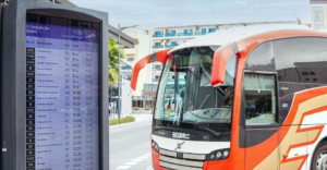 Digital route and timetable display board next to a public bus at a Dubai bus station, Khaleej Fusion