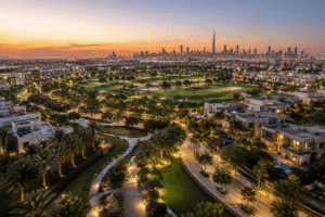 Aerial twilight view of Dubai Hills Estate featuring lush greenery, residential villas, and the distant Dubai skyline, Khaleej Fusion
