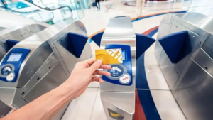 Person holding a Gold Nol Card and tapping it on a public transport station turnstile gate in Dubai, Khaleej Fusion