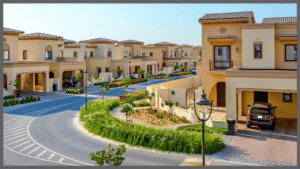 Street-level view of contemporary townhouses, landscaped roundabouts, and parked cars in a suburban Dubai residential community, Khaleej Fusion