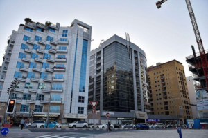 Street-level view of multi-story apartment buildings, commercial properties, and a construction crane along a Dubai street, Khaleej Fusion
