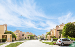 Street-level view of low-rise villas, landscaped greenery, and parked cars in a quiet Dubai residential community, Khaleej Fusion