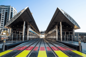 Perspective view of modern Dubai Tram tracks leading into a covered station platform with glass screen doors, Khaleej Fusion